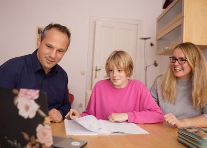 Family engaged in online learning together at home using laptop, focusing on education and connection.